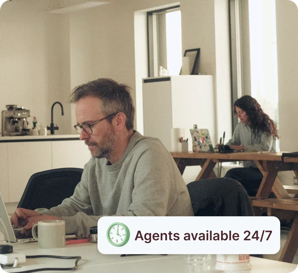 Person working on a laptop with an ANNA badge reading ‘Agents available 24/7’